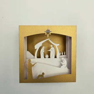 Crèche de Noël en papier découpé en relief, représentant la Nativité dans un encadrement doré